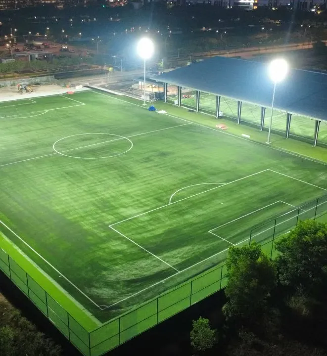 The full-size 11-a-side pitch at Batu Kawan under LED floodlights at night, with the roof of the covered pitch alongside