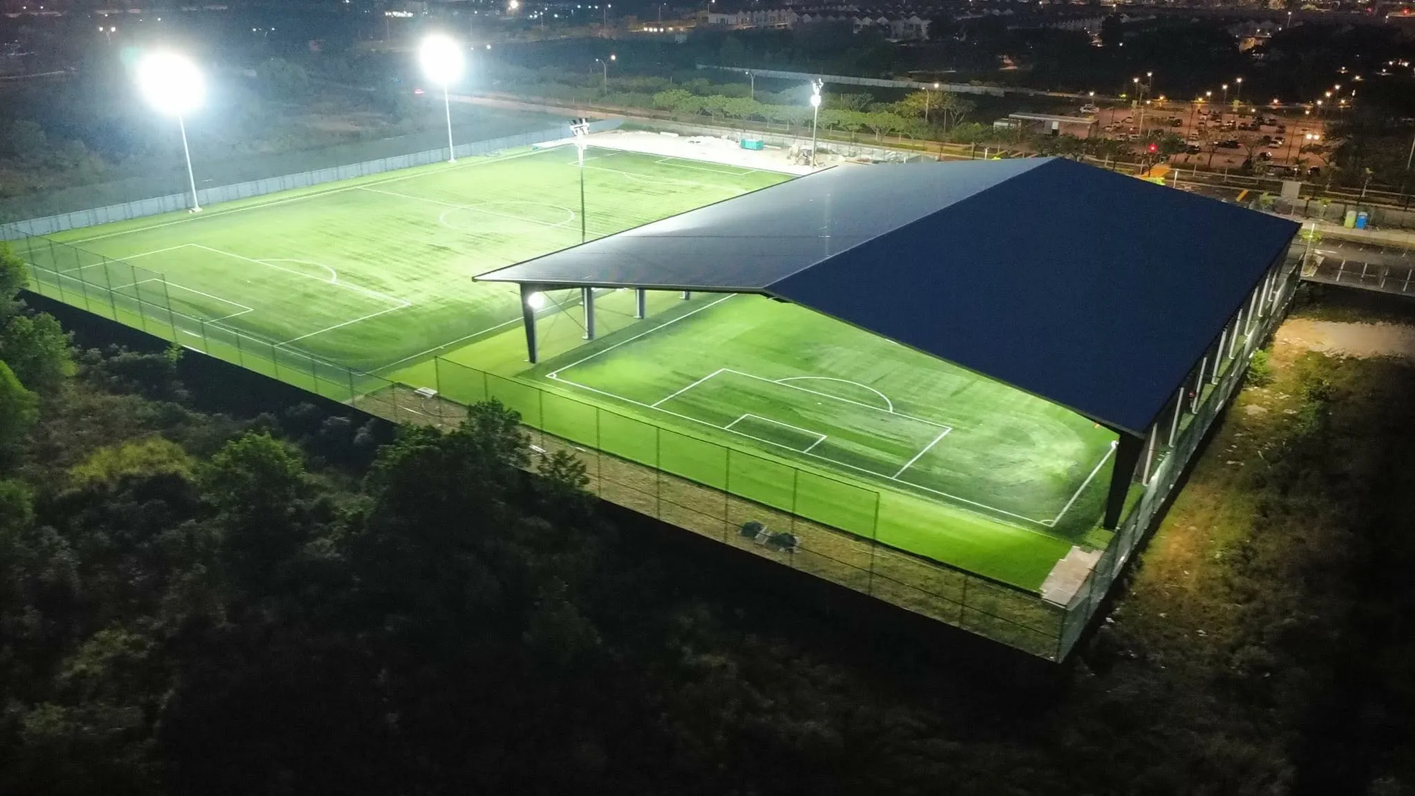 The covered 7-a-side and 9-a-side pitch at Soccer Experience Batu Kawan under floodlights during evening play