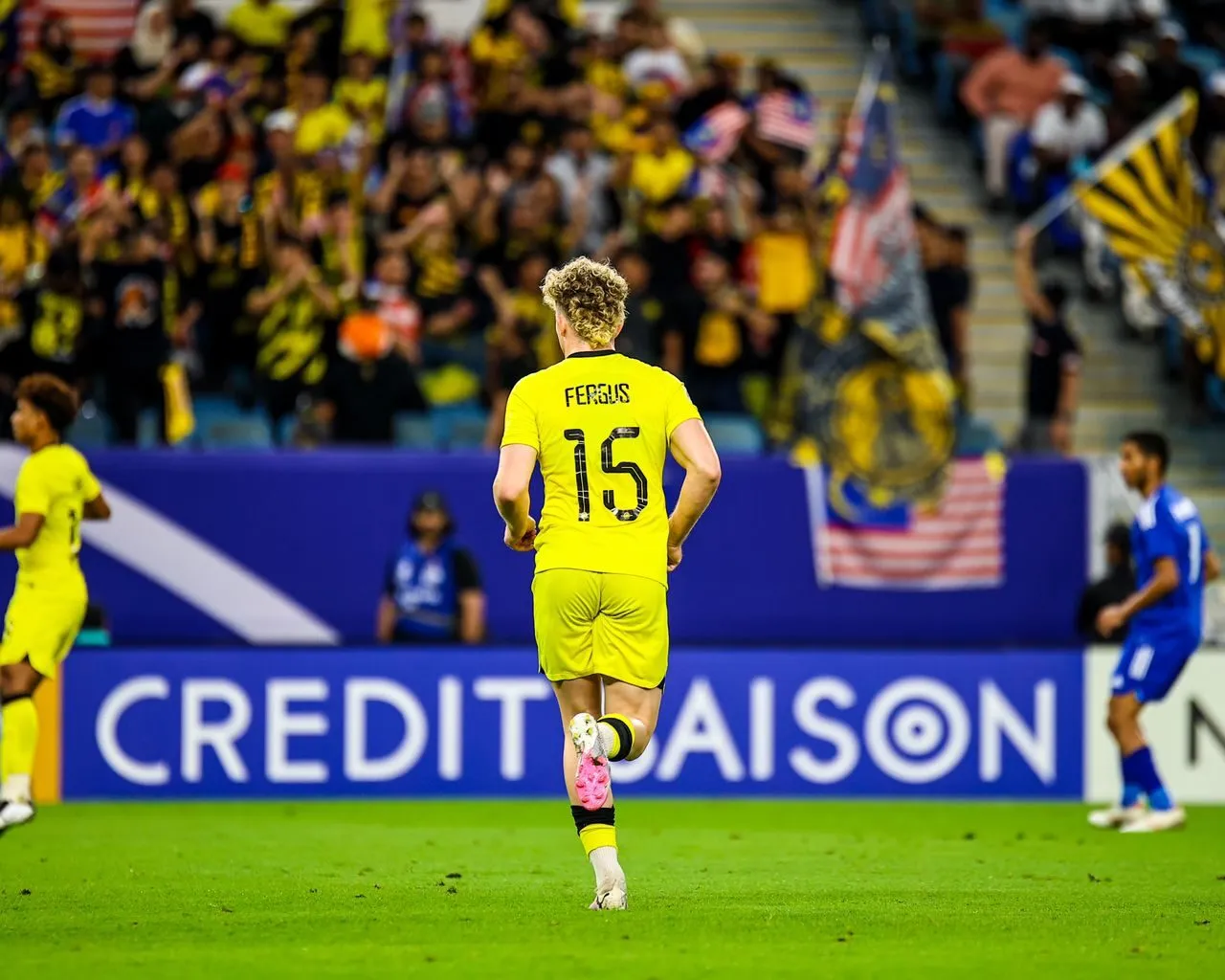 Fergus Tierney playing in the yellow shirt of the Malaysian national team in front of Malaysian supporters