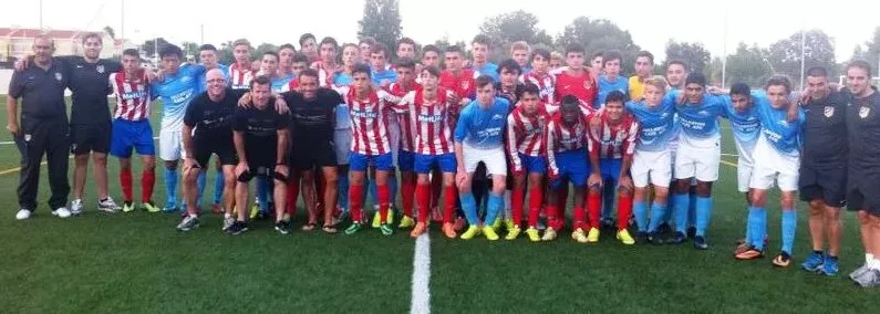 A Soccer Experience select side lined up alongside an Atlético Madrid team in red and white stripes