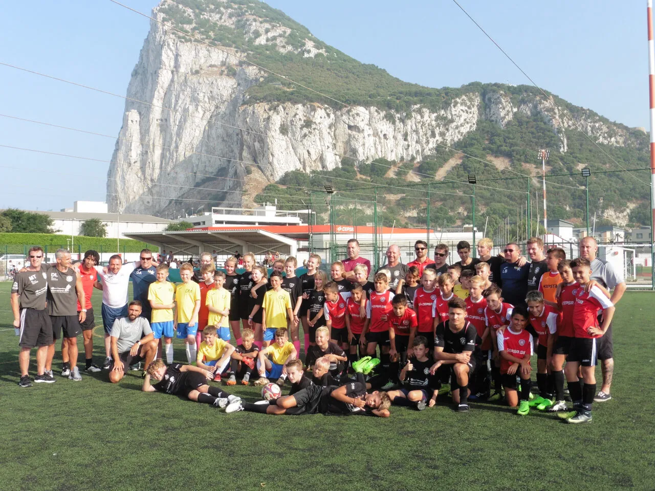 Youth teams lined up on a pitch beneath the Rock of Gibraltar before a Soccer Experience fixture