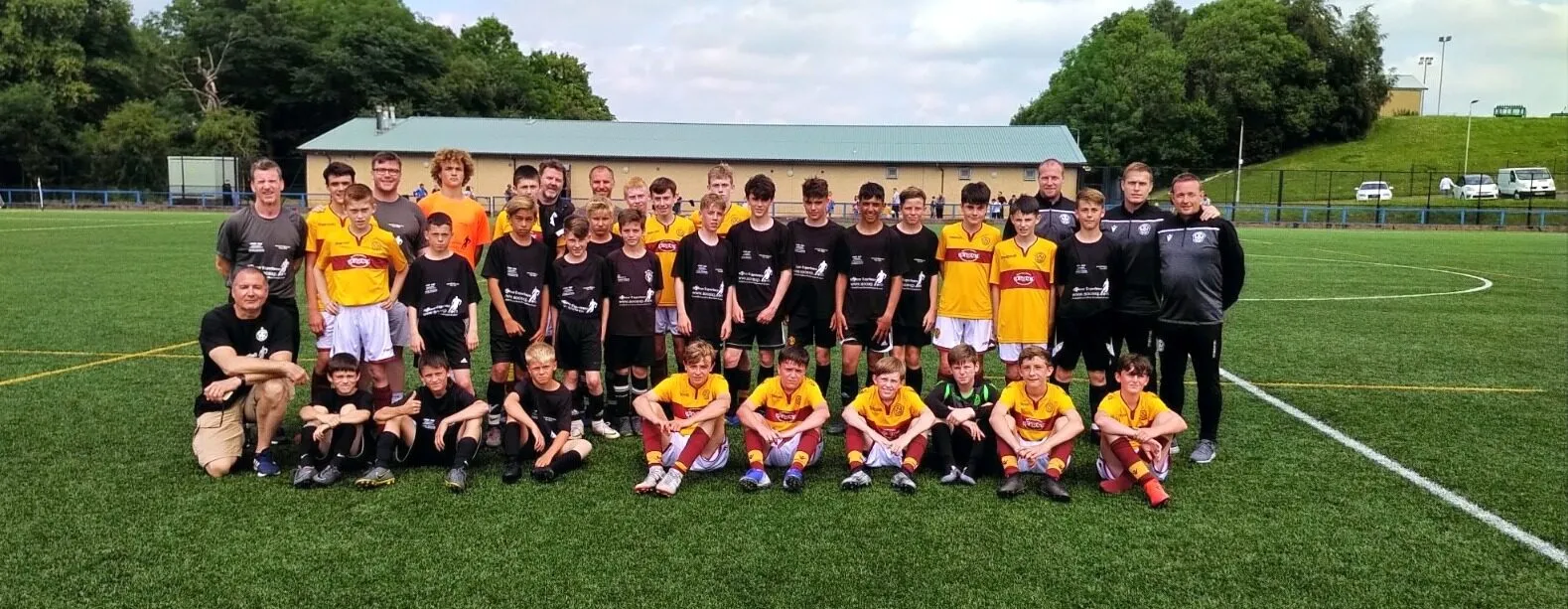 Two youth teams in yellow and black lined up together on a pitch during a Soccer Experience UK tour