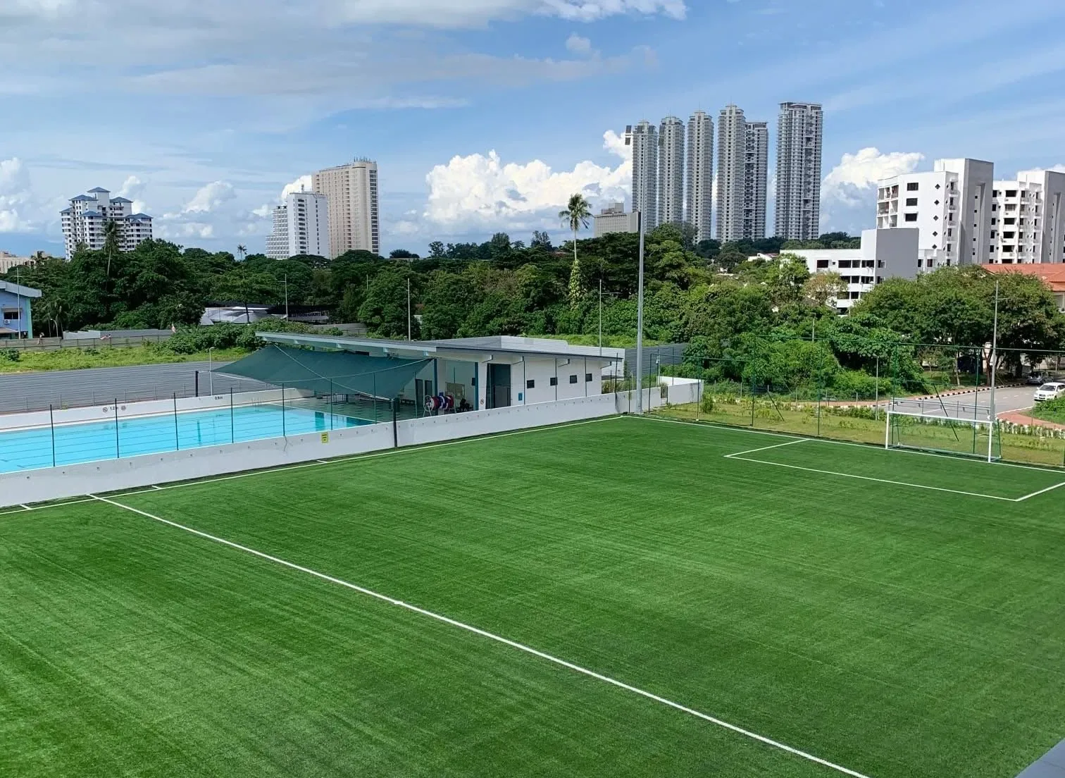 The full 9-a-side pitch at Tanjung Bungah from the raised end, with the swimming pool and clubhouse to one side and the goal at the far end